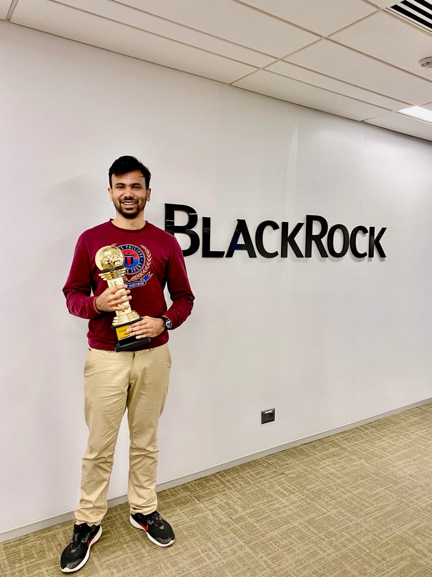 Kunal holding a trophy at the BlackRock office