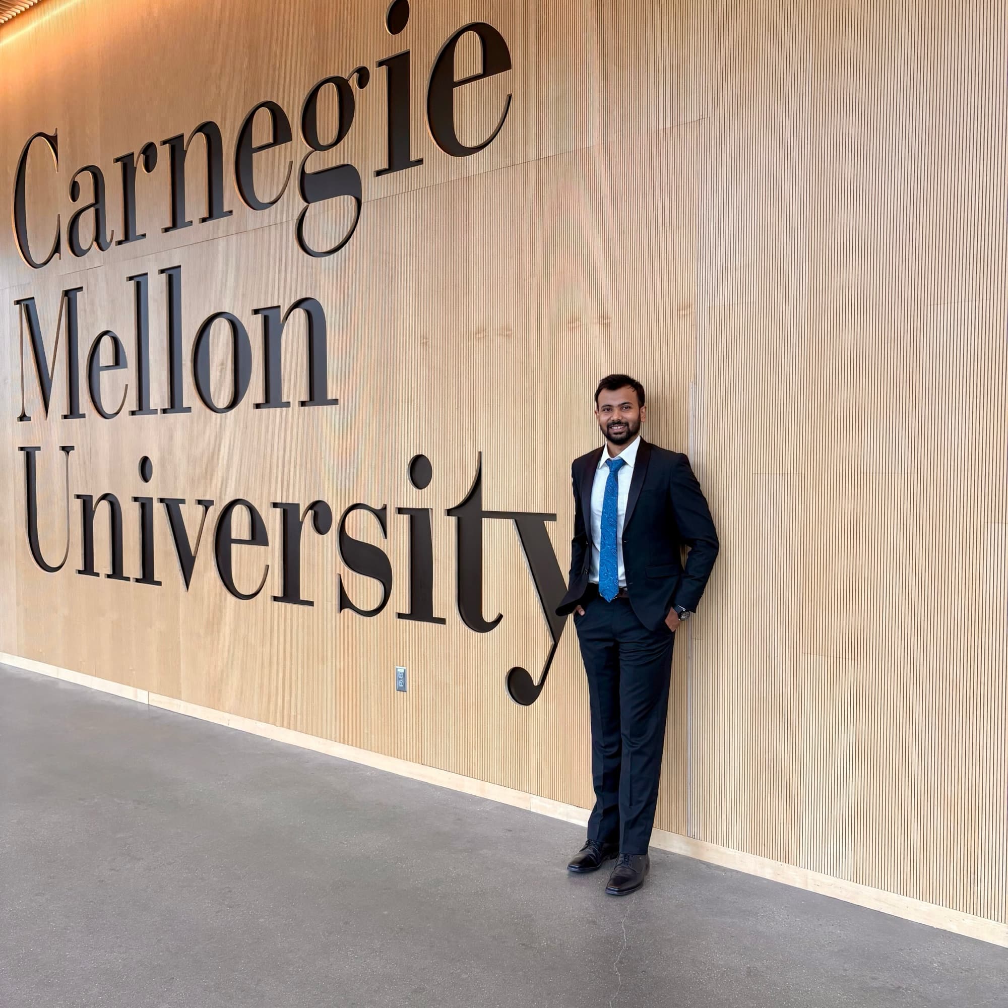 Kunal Pradyuman in a suit in front of the Carnegie Mellon University wall